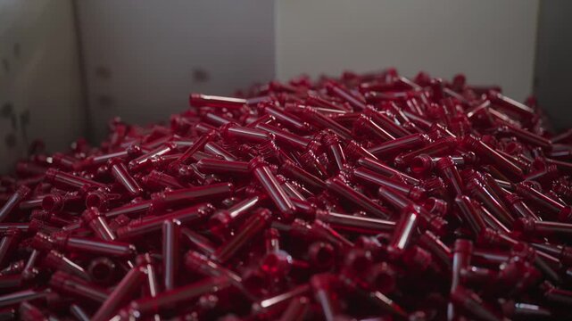 Red plastic preforms for PET bottles in manufacturing factory, close-up industrial production.