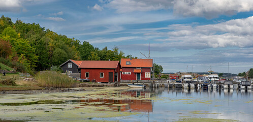 traditional red cabin in Fjalbacka village on a pontoon in front of the sea with boats in marina under sky in sweden © coco