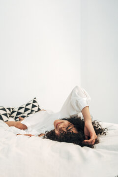 Content woman smiling relaxing on white clean bed