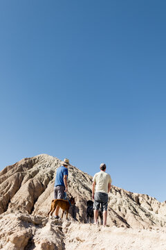 Two Middle Aged Men Standing with Dogs in Desert in CA