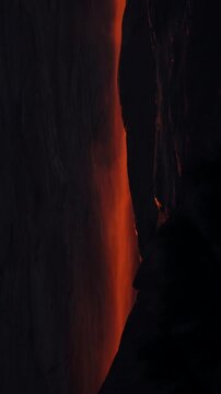Vertical Screen: Yosemite National Park Firefall phenomenon with glowing orange waterfall cascading down dark granite cliff face during sunset, creating molten lava effect