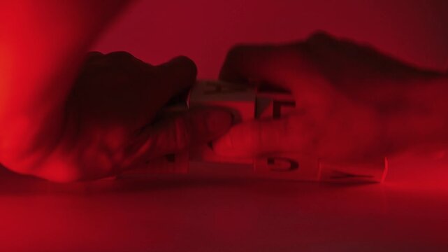 Blocks with letters are arranged and moved to spell words related to emotions. The setting features bright red lighting which adds intensity to the concept