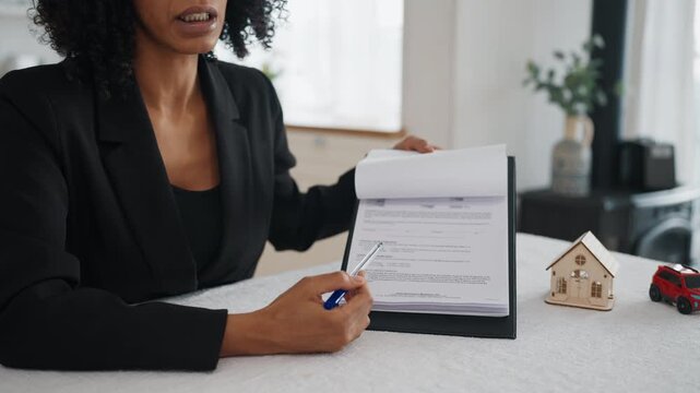 Presentation of mortgage or insurance agreement, real estate broker talking. African american woman showing papers for clients and explaining conditions of installment plan and bank credit service