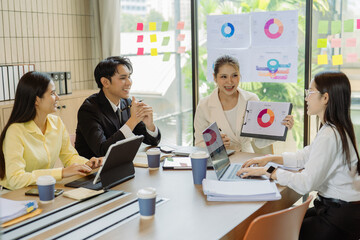 Fototapeta premium A group of Asian business leaders are discussing charts and graphs that illustrate the results of teamwork and explaining the data to their colleagues.