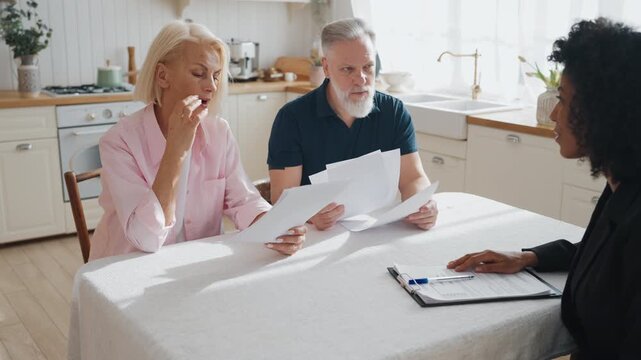 Aged people consulting with professional lawyer, man and woman reading contract. Senior spouses viewing agreements with real estate agency, examining conditions, rights and obligations of parties