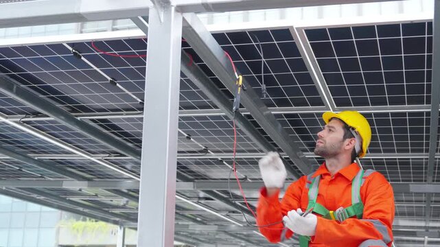 Male engineer inspecting electrical wiring under solar panels using clamp meter checking current and voltage renewable energy system technician maintenance industrial electrical inspection process