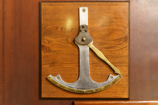 Vintage clinometer mounted on wooden panel, antique angle measuring instrument