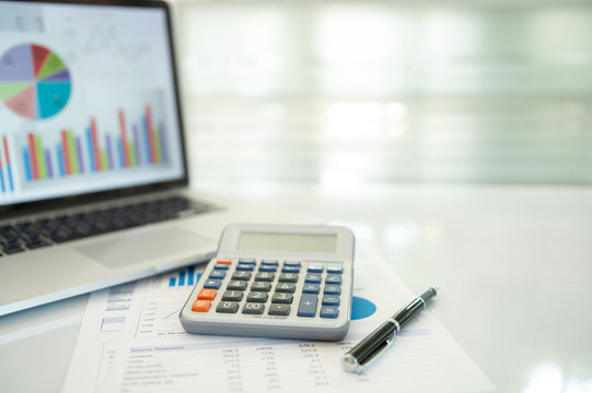 calculator and Financial reports on the investment portfolio of stock market, chart values ​​displayed on a laptop screen. finance and investment concept.
