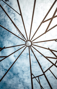 Circular wooden roof frame pattern viewed from below against sky
