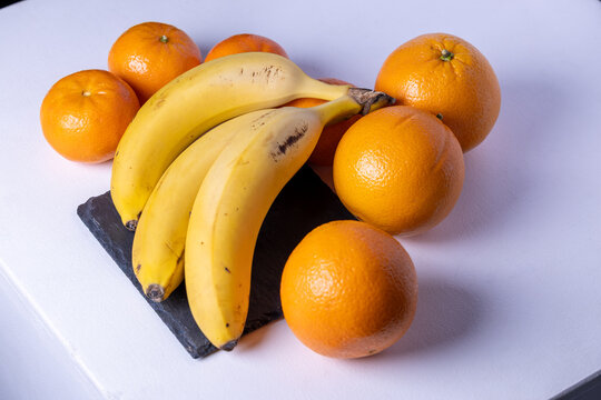 Bananas and oranges arranged on a table with natural light. Fresh fruit, healthy food and minimal composition ideal for nutrition concepts.
