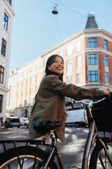 Smiling woman with bicycle in sunny city street © Jacob Lund