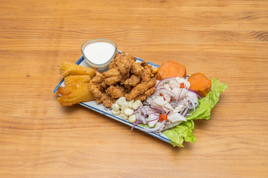 A deep plate of mixed Peruvian ceviche featuring pieces of white fish, calamari rings, whole prawns, and scallops, all bathed in a thick leche de tigre