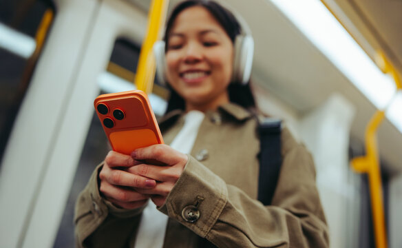Commuter smiling while using phone with headphones