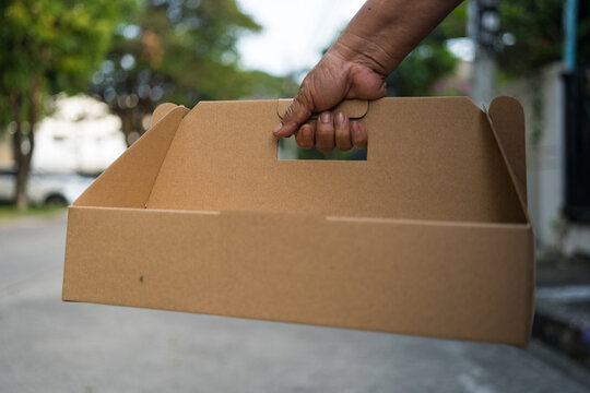 A plain brown cardboard takeaway box with handle
