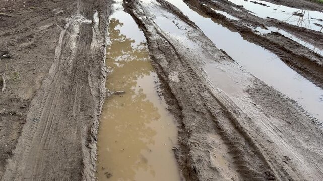 Brown water sits in deep tire tracks on a messy dirt road. The scene feels lonely and damp under a gray sky. This quiet path shows the simple, rugged beauty of the countryside after a storm.