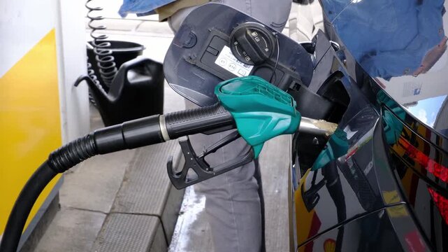 Mid Shot of Unrecognizable Man Hands Holding Fuel Pump Handle While Refueling Car at Gas Station During Rising Fuel Prices and Cost of Living Increase, Part of a Series.