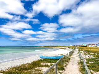 Fototapeta premium Small rowboat dinghy on a beach beneath beautiful blue azure sky