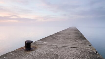 Fototapeta premium Minimalist view of an empty concrete pier at dawn with a mooring bollard. Peaceful maritime landscape representing potential, space, and the quiet side of harbor logistics.