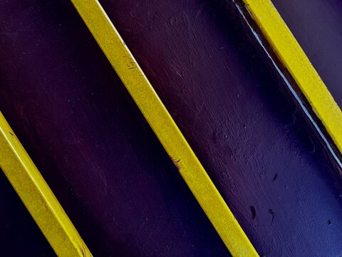 Abstract Composition of Parallel Yellow Lines on a Dark Purple Textured Surface
