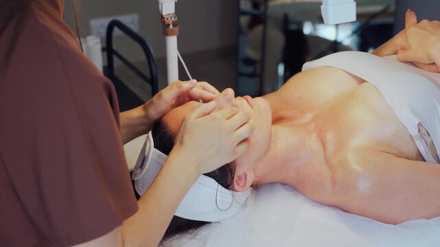 Acupressure and sculpting techniques. Therapist performs targeted facial acupressure and sculpting pinches. Professional applies specific finger pressure and pinches to enhance facial contours