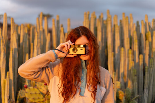 Portrait with camera outdoors at sunset among cactus plants
