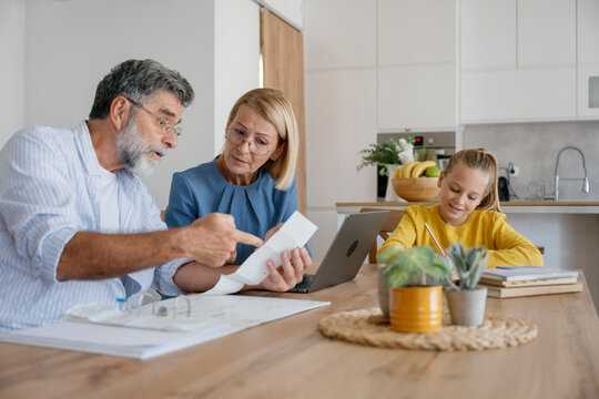 Couple checking bills and child doing homework at home