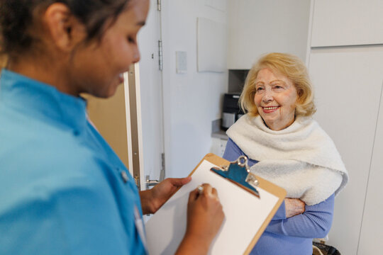 Nurse assisting elderly woman during home medical checkup