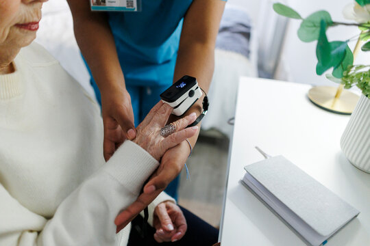 Nurse measuring oxygen level with pulse oximeter at home