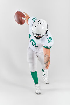 American football player in full gear running with ball on white background