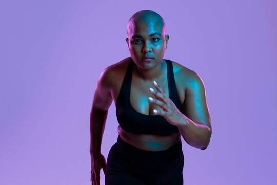 Athlete in sportswear sprinting with determination in a studio setting