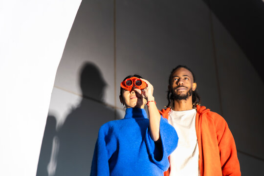 Two people with red binoculars exhibiting curiosity