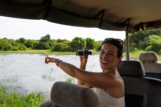 Smiling tourist with binoculars on safari jeep in Sigiriya Sri Lanka
