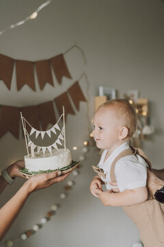 Parent and child celebrating first birthday with festive cake indoors