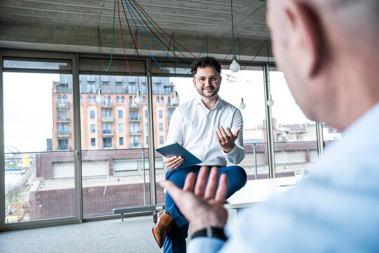 Businessmen discussing ideas with tablet in modern office