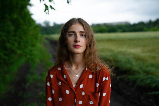 Woman with curly hair in red polka dot blouse outdoors in nature