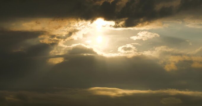 Timelapse footage of light beams among clouds in a gloomy sky covered with rain and storm clouds.
