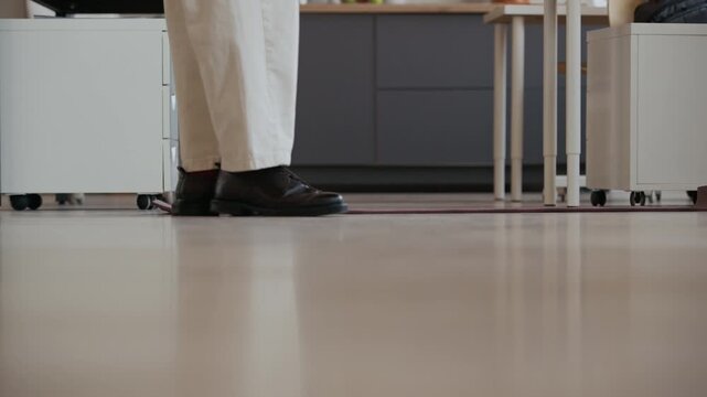 Ground level shot of legs of unrecognizable male office worker rolling out yoga mat, taking off shoes and starting exercising