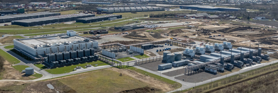 Large-scale data center campus with extensive computing facilities, dedicated energy supply systems, and advanced cooling infrastructure with extended infrastructure under construction.