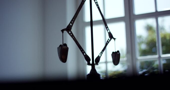 Vintage metal balance scale standing in front of window in bright room with blurred background