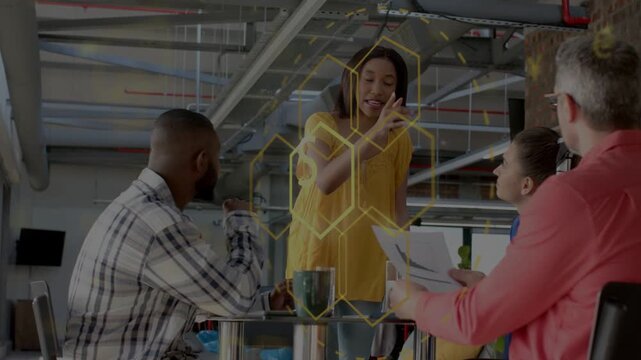Leading woman in yellow top making point, sweeping in meeting seeking decision with hex overlay