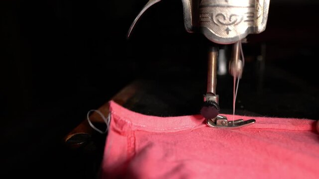 An old sewing machine in operation, sewing fabric on a machine