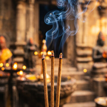 Incense sticks burning with smoke in a spiritual temple setting