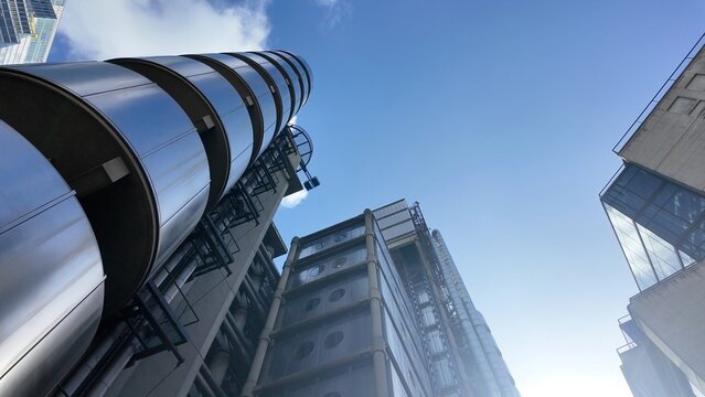 Lloyd's building exterior showcasing its unique high-tech architecture with visible infrastructure and reflective metallic facades against a clear blue sky