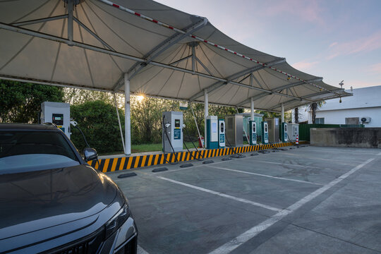 Modern EV Charging Station with Canopy at Dusk, One Car Plugged In