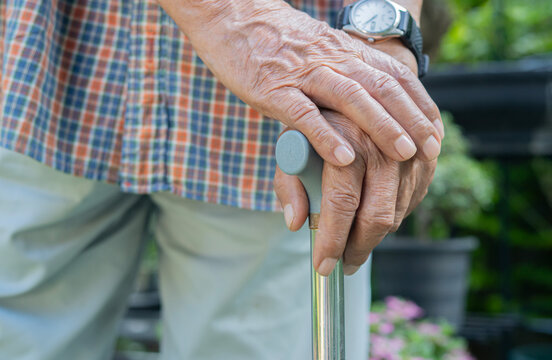 Close-up an old man's hands holding walking cane at outdoor. Walking sticks for the elderly