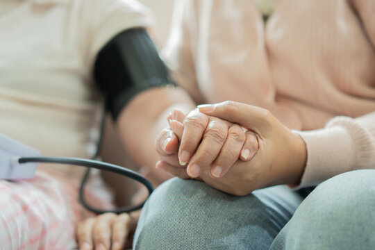 Close-up image of a caregiver's holding hand of the elderly female patient