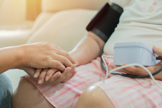 Selective foucus of nurse holding hands of elderly patient with care while measuring blood pressure
