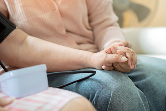 The adult daughter held her elderly mother's hand affectionately while measuring a blood pressure