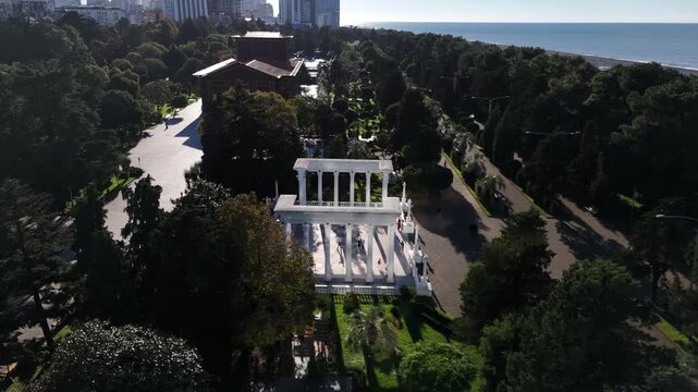 Drone view of the white colonnades on the Batumi Boulevard in Georgia with people walking in the park area.