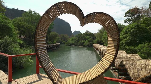 Push back from a heart shaped frame with riverside bungalows floating on the river.